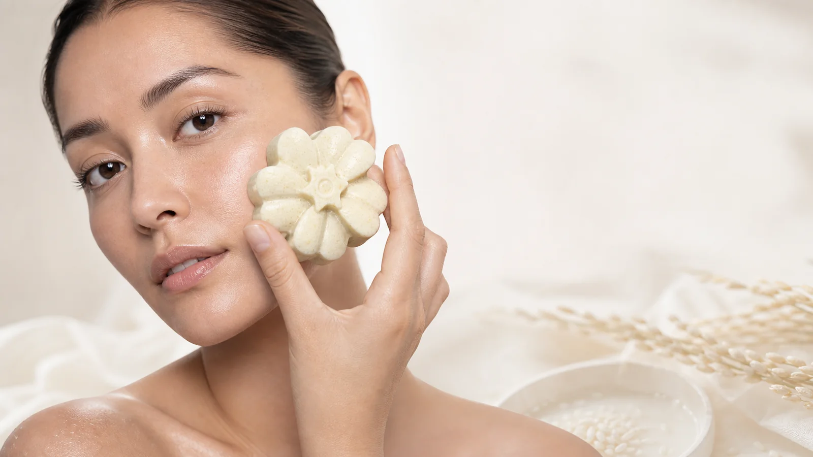 Modelo sosteniendo un jabón artesanal con espuma junto al rostro, composición editorial
